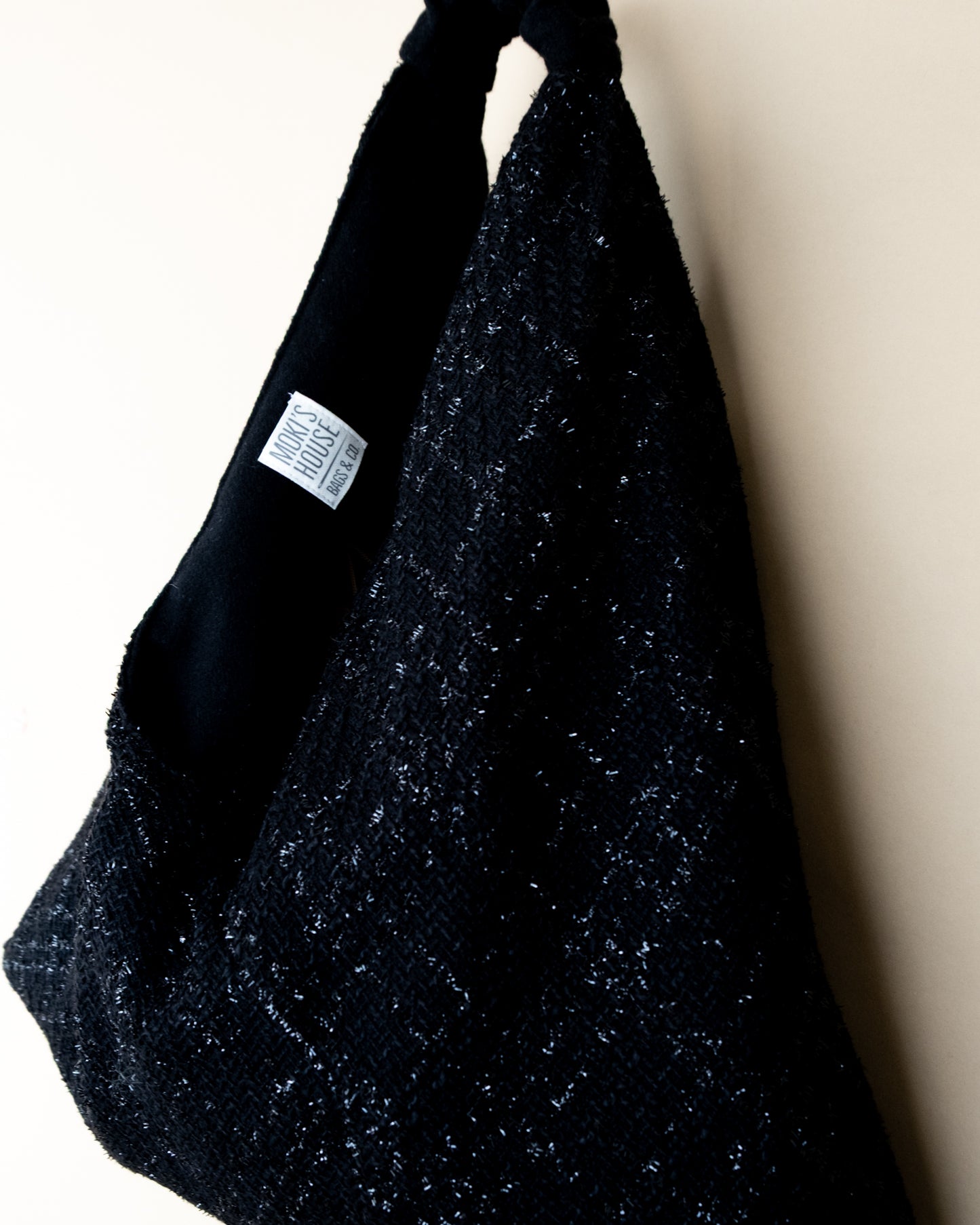 Vista laterale borsa Peggie con dettaglio reversibilità lamè e lana